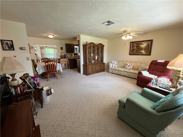 carpeted living room featuring ceiling fan and a textured ceiling