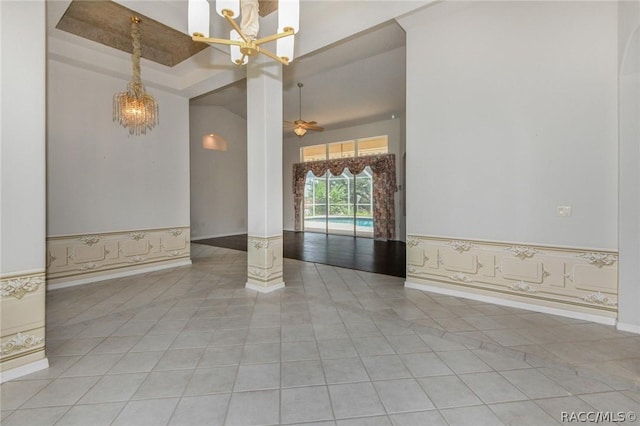 unfurnished room featuring ceiling fan with notable chandelier, light tile patterned floors, and a towering ceiling