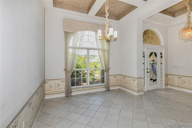 tiled spare room with a chandelier, beam ceiling, and coffered ceiling