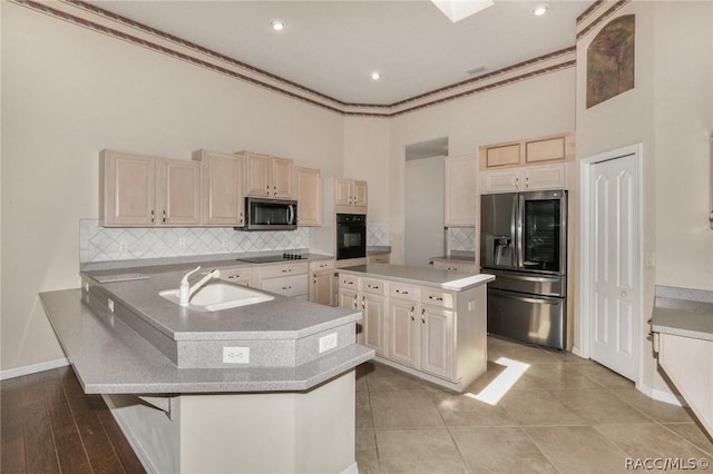 kitchen featuring backsplash, black appliances, sink, an island with sink, and a breakfast bar area