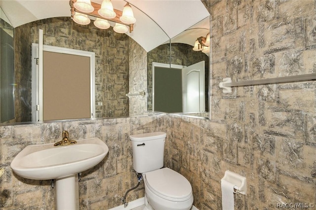 bathroom featuring toilet, lofted ceiling, and sink