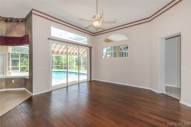 unfurnished room with ceiling fan, ornamental molding, and dark wood-type flooring