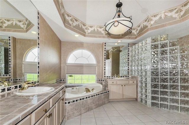 bathroom featuring vanity, a raised ceiling, tile patterned flooring, a wealth of natural light, and tiled bath