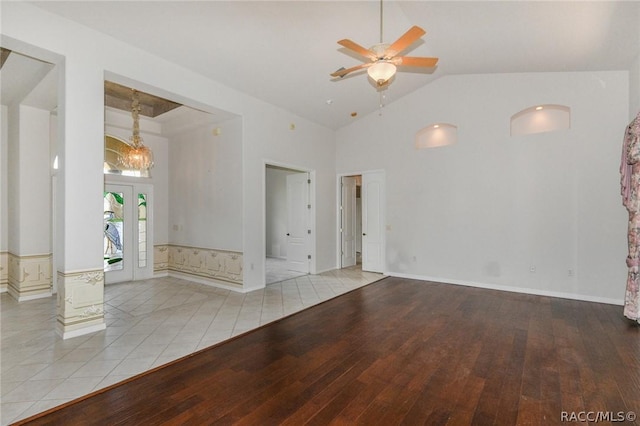 unfurnished room featuring ceiling fan with notable chandelier, french doors, light wood-type flooring, and high vaulted ceiling