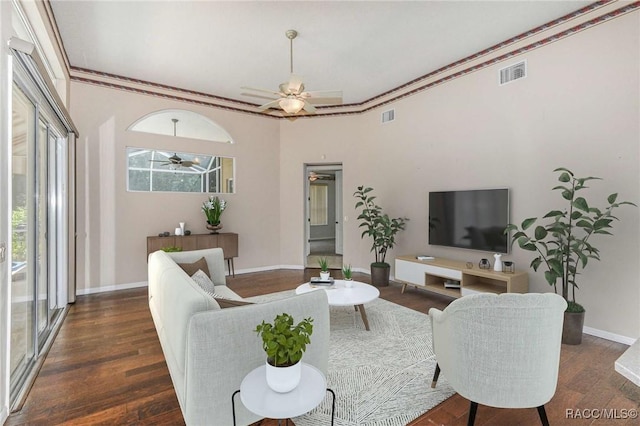 living room with ornamental molding, ceiling fan, and dark wood-type flooring