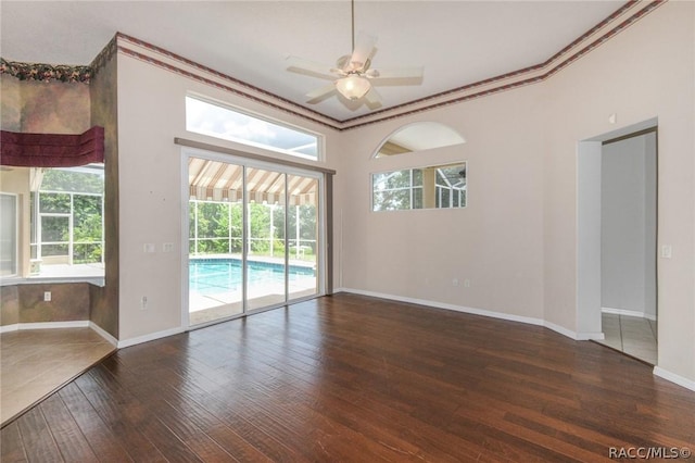 empty room with ceiling fan, crown molding, and dark wood-type flooring