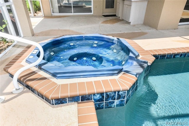 view of swimming pool featuring a patio area and an in ground hot tub