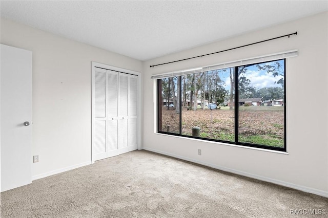 unfurnished bedroom featuring carpet floors, a textured ceiling, and a closet