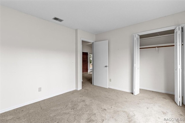 unfurnished bedroom featuring light carpet and a closet