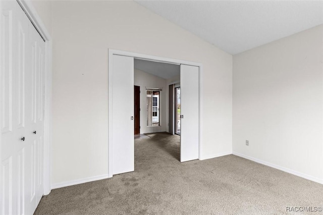 carpeted spare room featuring lofted ceiling