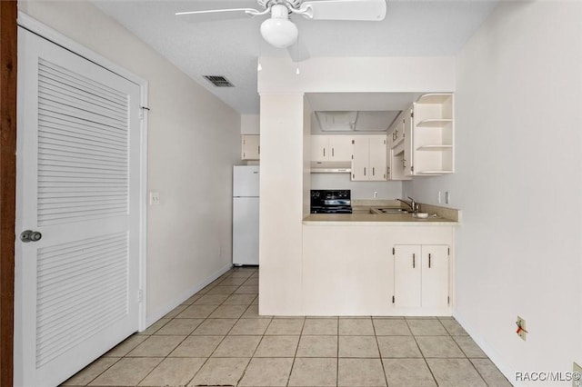 kitchen with white cabinetry, range, light tile patterned flooring, and white fridge