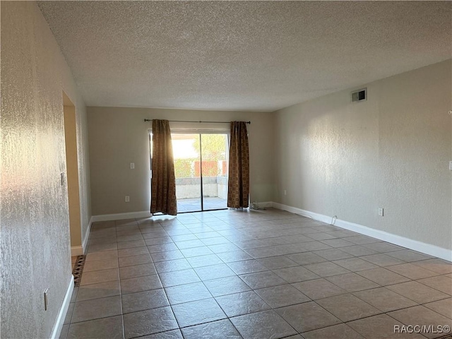 tiled spare room featuring a textured ceiling