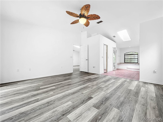 unfurnished living room featuring ceiling fan, light wood-type flooring, and lofted ceiling with skylight