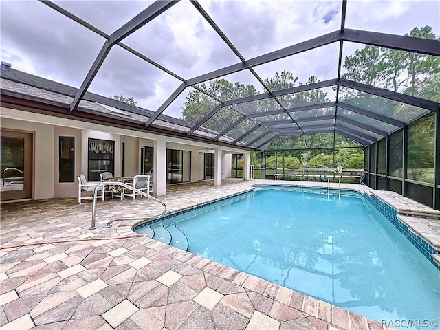 view of swimming pool featuring glass enclosure and a patio area