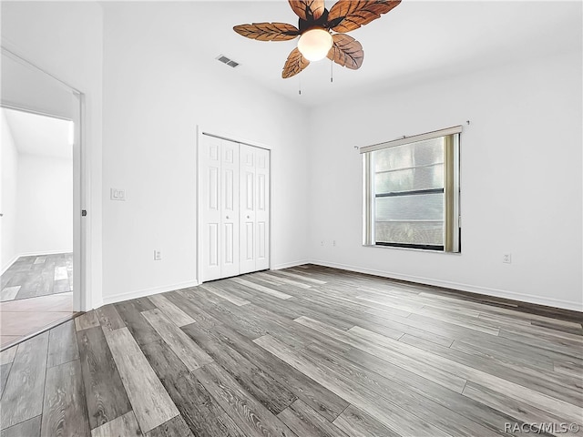 unfurnished bedroom with a closet, hardwood / wood-style floors, and ceiling fan