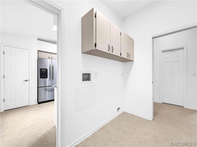 clothes washing area with cabinets, washer hookup, and light tile patterned floors