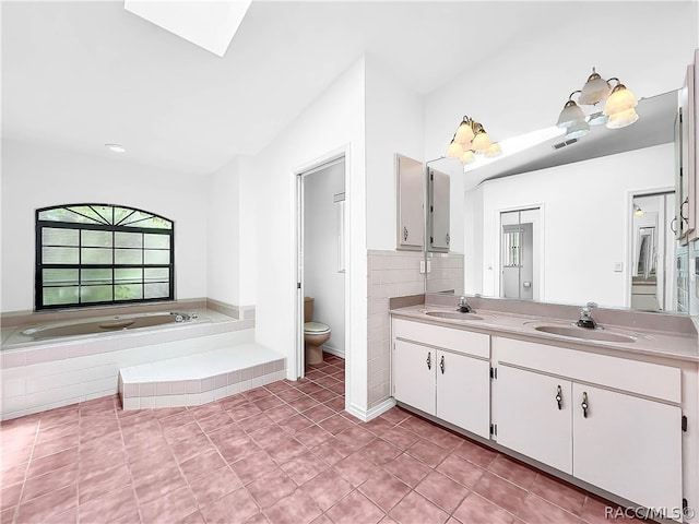 bathroom featuring vanity, tile patterned floors, vaulted ceiling, toilet, and tiled tub