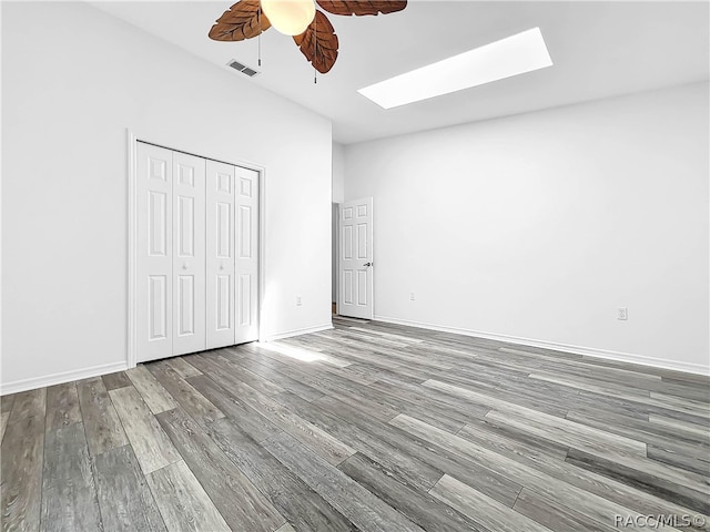 unfurnished bedroom with a skylight, light hardwood / wood-style flooring, a closet, and ceiling fan