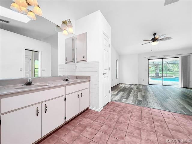 kitchen with lofted ceiling, white cabinets, sink, ceiling fan, and light hardwood / wood-style floors