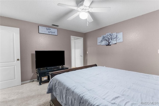 carpeted bedroom with ceiling fan and a textured ceiling