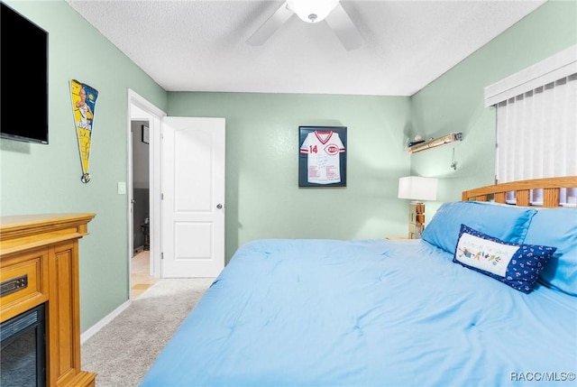 bedroom featuring light carpet, ceiling fan, and a textured ceiling