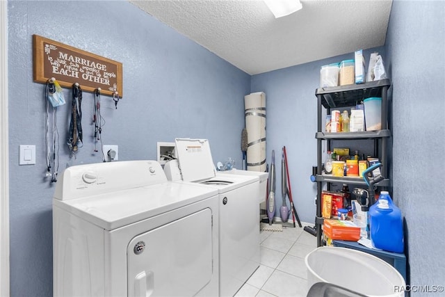 laundry room featuring washing machine and dryer, a textured ceiling, and light tile patterned floors