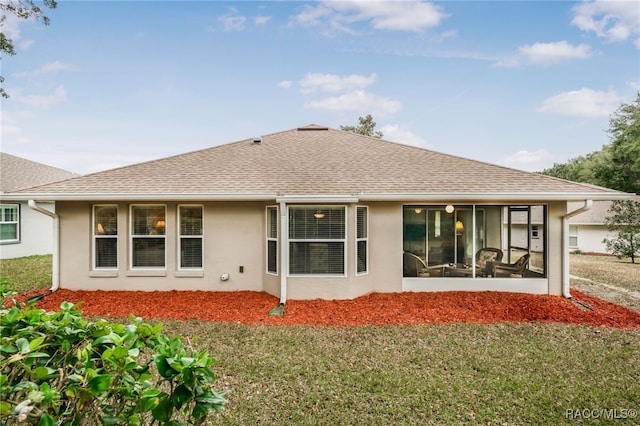 rear view of property featuring a yard and a sunroom