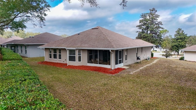 rear view of house featuring a yard and a sunroom