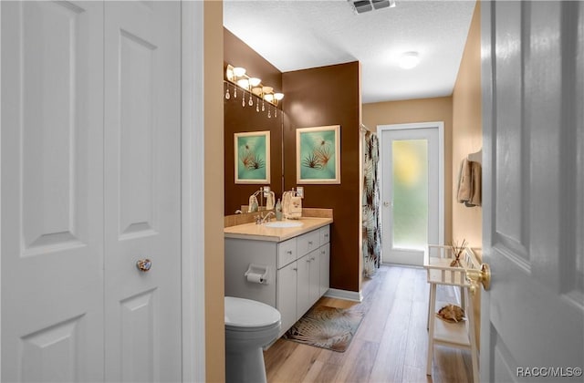 full bathroom featuring wood finished floors, visible vents, toilet, vanity, and baseboards