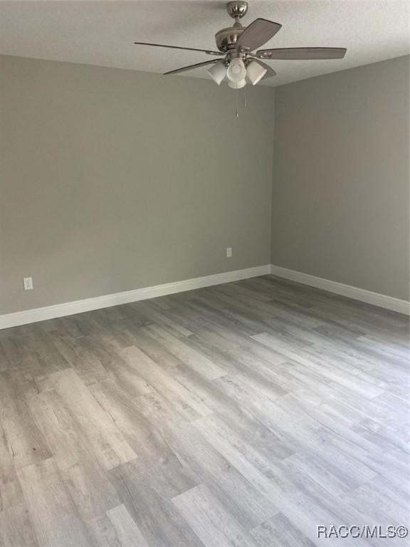 unfurnished room featuring ceiling fan, light hardwood / wood-style flooring, and a textured ceiling