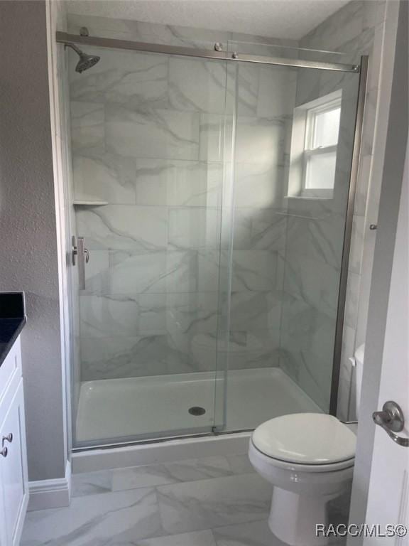 bathroom featuring vanity, toilet, and a shower with shower door