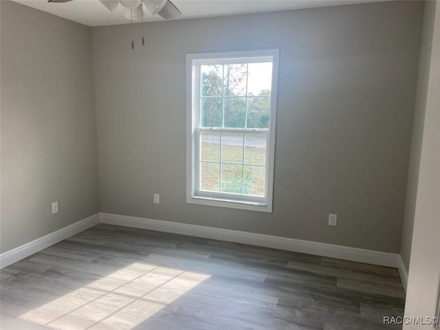 spare room with ceiling fan, plenty of natural light, and light wood-type flooring