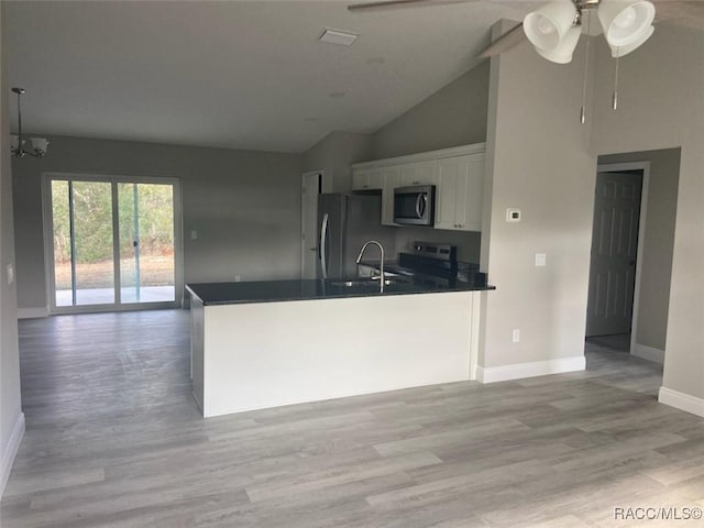 kitchen with appliances with stainless steel finishes, high vaulted ceiling, white cabinets, light hardwood / wood-style floors, and kitchen peninsula