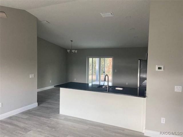 kitchen with lofted ceiling, sink, fridge, a notable chandelier, and wood-type flooring