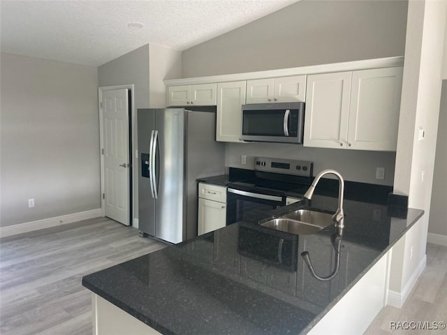 kitchen featuring sink, white cabinets, kitchen peninsula, stainless steel appliances, and light hardwood / wood-style flooring