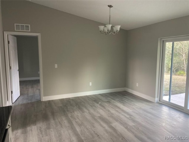 unfurnished room with wood-type flooring, vaulted ceiling, and a notable chandelier