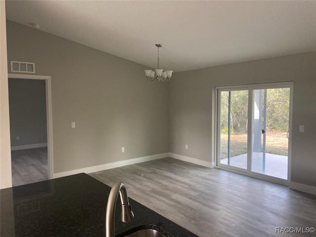 spare room with dark hardwood / wood-style flooring, vaulted ceiling, and a chandelier