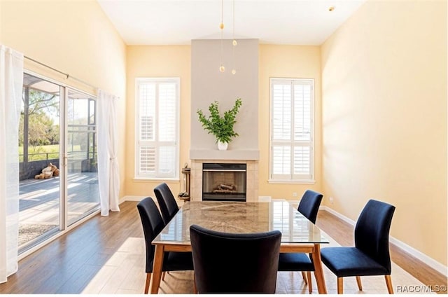 dining space with wood-type flooring and a tiled fireplace