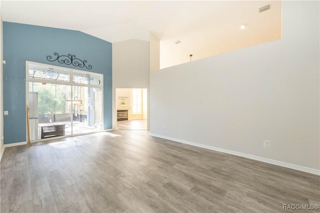 unfurnished living room with hardwood / wood-style flooring and high vaulted ceiling