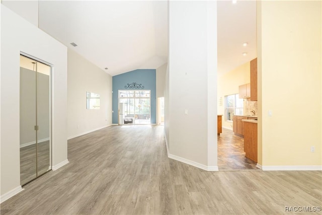 interior space featuring plenty of natural light, high vaulted ceiling, and light hardwood / wood-style flooring