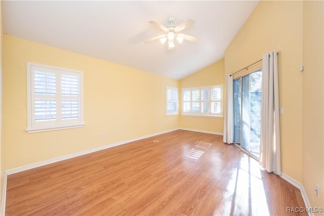 empty room with a wealth of natural light, ceiling fan, light hardwood / wood-style flooring, and vaulted ceiling