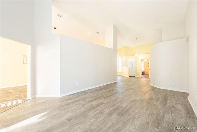 empty room featuring wood-type flooring and a towering ceiling