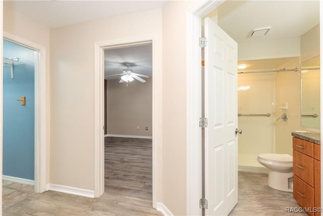 bathroom featuring walk in shower, vanity, ceiling fan, hardwood / wood-style flooring, and toilet