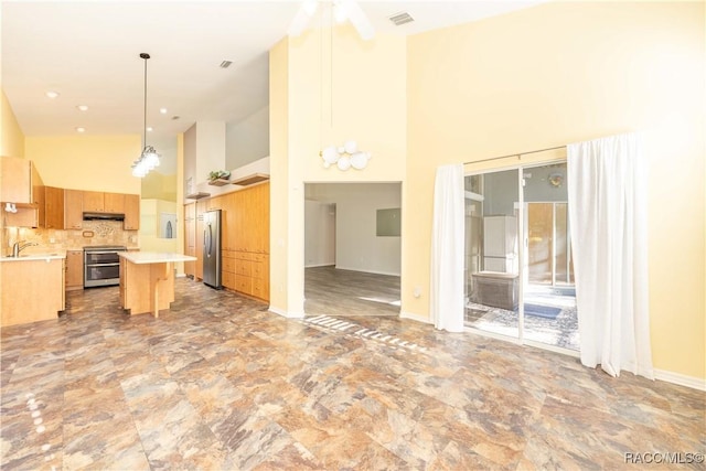 kitchen with a center island, stainless steel appliances, a high ceiling, pendant lighting, and a breakfast bar area