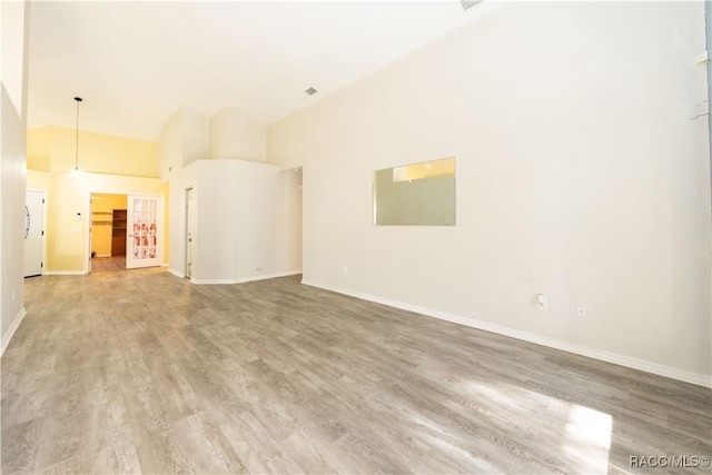 unfurnished living room with wood-type flooring and a high ceiling