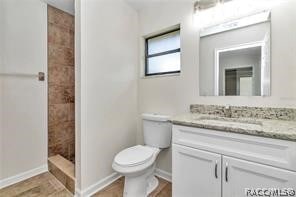 bathroom with toilet, a shower, and vanity