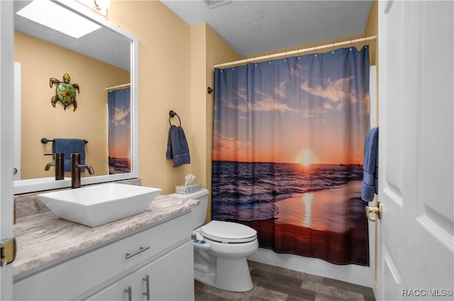 bathroom with a shower with curtain, vanity, toilet, and a textured ceiling