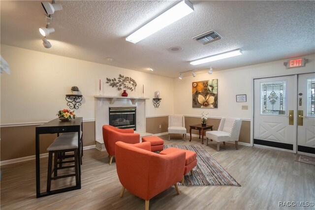 living room with hardwood / wood-style floors, a high end fireplace, rail lighting, and a textured ceiling