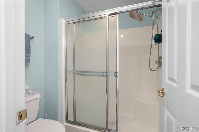 bathroom featuring toilet and a shower with shower door