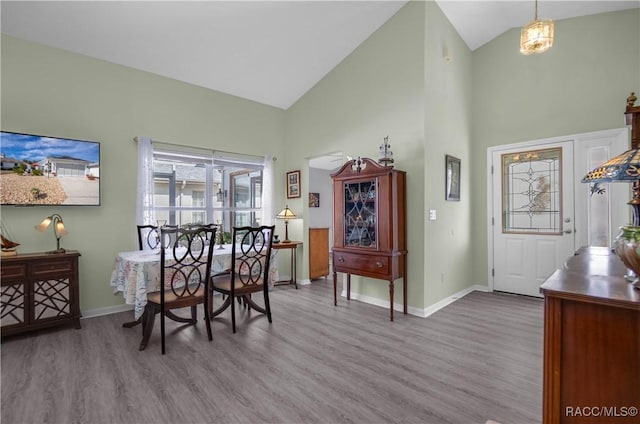 dining area featuring high vaulted ceiling and light wood-type flooring